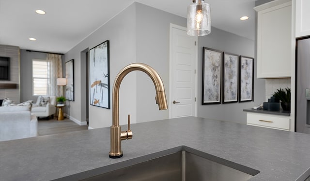 interior details featuring tasteful backsplash, sink, pendant lighting, and white cabinets