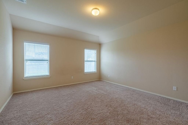 carpeted spare room featuring vaulted ceiling and a healthy amount of sunlight