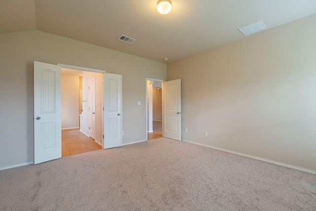 unfurnished bedroom featuring light colored carpet and lofted ceiling