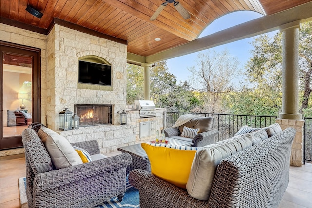 view of patio with ceiling fan, grilling area, an outdoor living space with a fireplace, and exterior kitchen