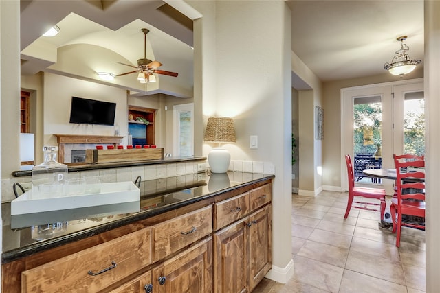 kitchen with ceiling fan, a fireplace, light tile patterned flooring, and lofted ceiling