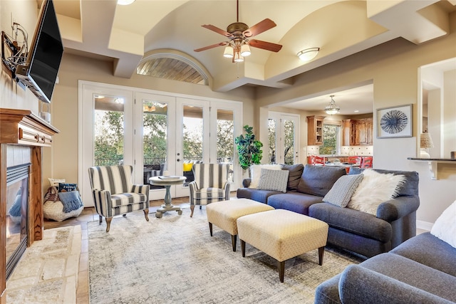 living room with lofted ceiling, a tile fireplace, french doors, and ceiling fan