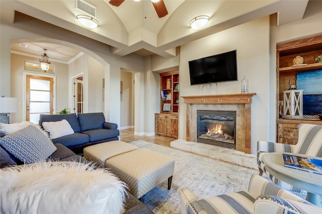 living room with ceiling fan, built in shelves, and crown molding