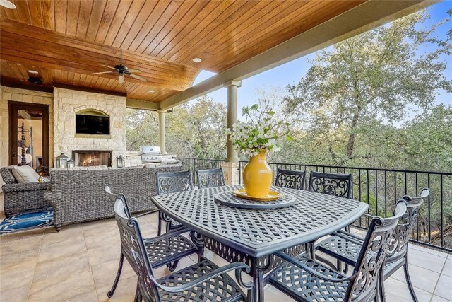 view of patio with ceiling fan, a grill, an outdoor stone fireplace, and an outdoor kitchen