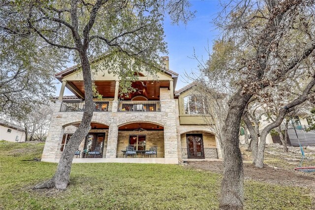 view of front of property with a balcony, a front lawn, ceiling fan, and a patio area