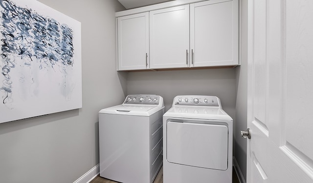 clothes washing area featuring cabinets and washer and dryer