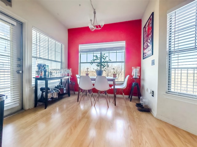 dining room with a healthy amount of sunlight, light hardwood / wood-style floors, and a notable chandelier