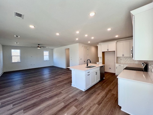 kitchen featuring dark wood-type flooring, sink, white cabinetry, an island with sink, and decorative backsplash