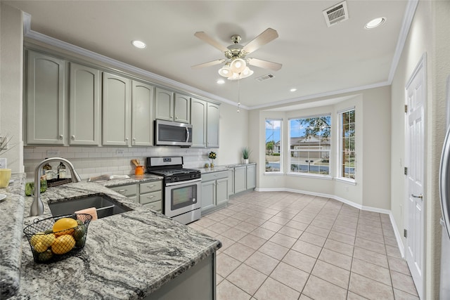 kitchen featuring light stone countertops, appliances with stainless steel finishes, sink, backsplash, and crown molding