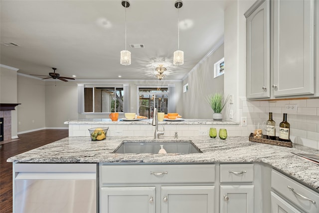 kitchen with white cabinets, light stone counters, a tile fireplace, and sink