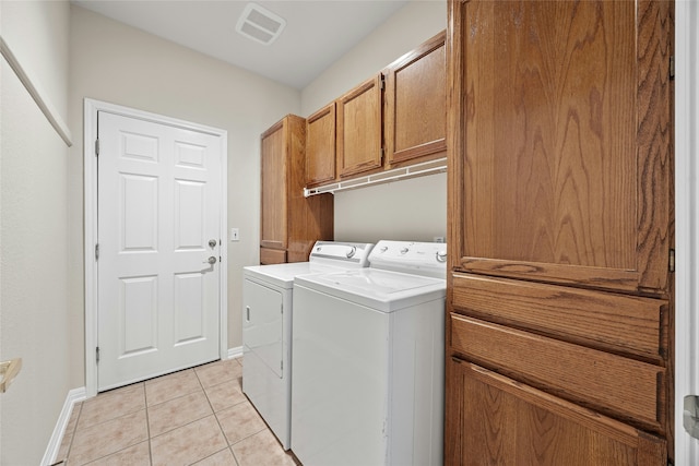 clothes washing area with light tile patterned flooring, washing machine and clothes dryer, and cabinets