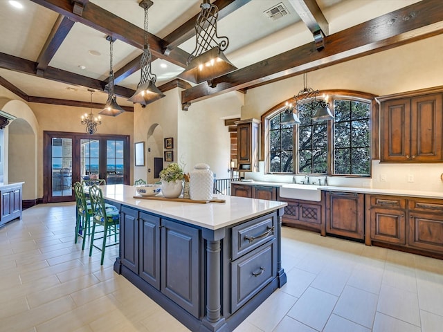 kitchen with a notable chandelier, beam ceiling, hanging light fixtures, and a center island