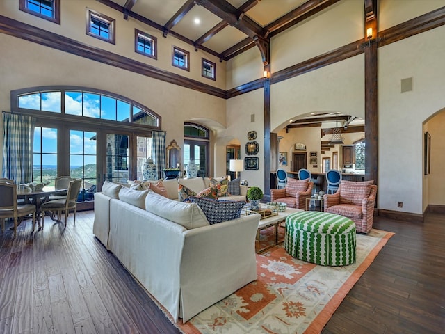 living room featuring dark wood-type flooring, beamed ceiling, a high ceiling, and coffered ceiling