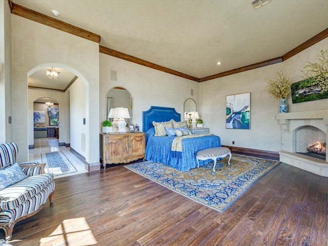 bedroom featuring dark hardwood / wood-style floors, ornamental molding, and an inviting chandelier