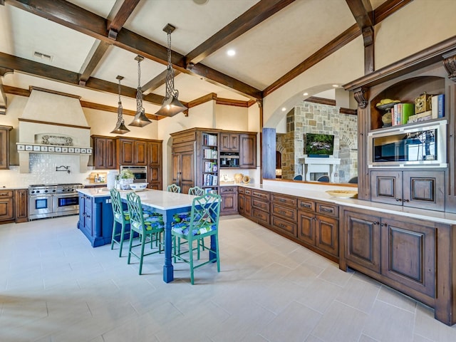 kitchen with a kitchen island, stainless steel appliances, backsplash, hanging light fixtures, and custom range hood