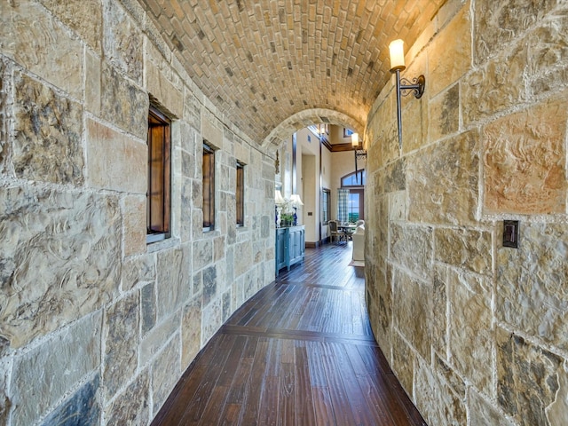 hallway featuring brick ceiling, dark hardwood / wood-style floors, and lofted ceiling