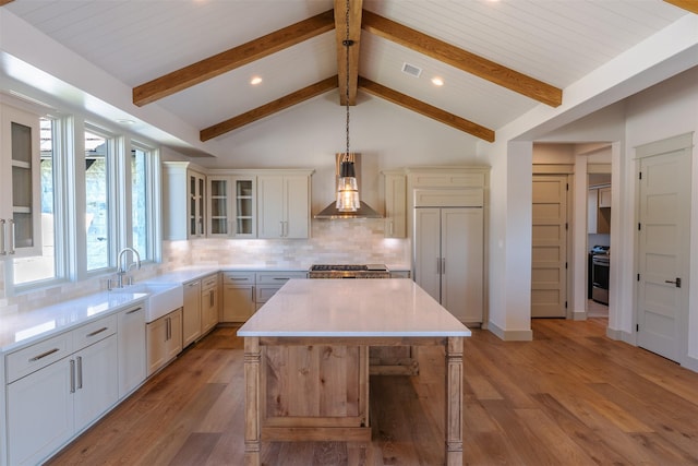 kitchen with backsplash, hanging light fixtures, wall chimney range hood, stainless steel range oven, and a kitchen island