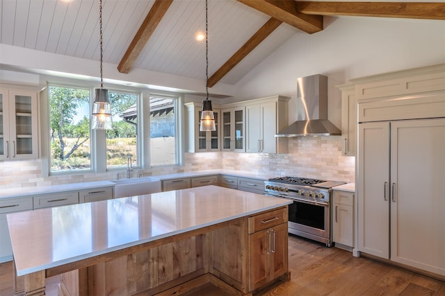 kitchen with double oven range, a center island, tasteful backsplash, wall chimney range hood, and sink