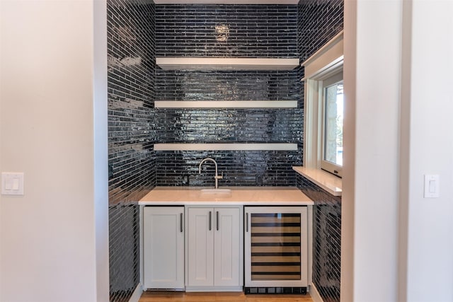 bar featuring sink, tile walls, backsplash, and beverage cooler