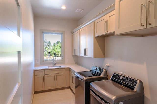 clothes washing area featuring washer and dryer, sink, and cabinets