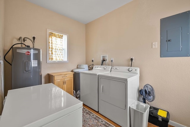 laundry room featuring water heater, washer and clothes dryer, cabinets, electric panel, and light hardwood / wood-style flooring