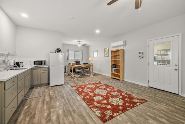 1881 County Road 251, Florence, TX 76527 - kitchen featuring freestanding refrigerator, ceiling fan, gray cabinets, wood finished floors, and a wall mounted air conditioner