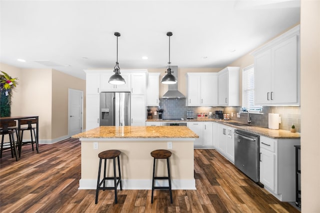 kitchen with a kitchen island, white cabinetry, stainless steel appliances, sink, and hanging light fixtures