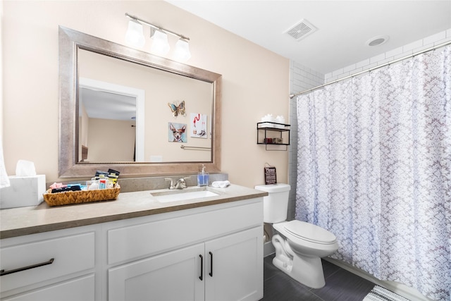 bathroom with toilet, vanity, and tile patterned flooring