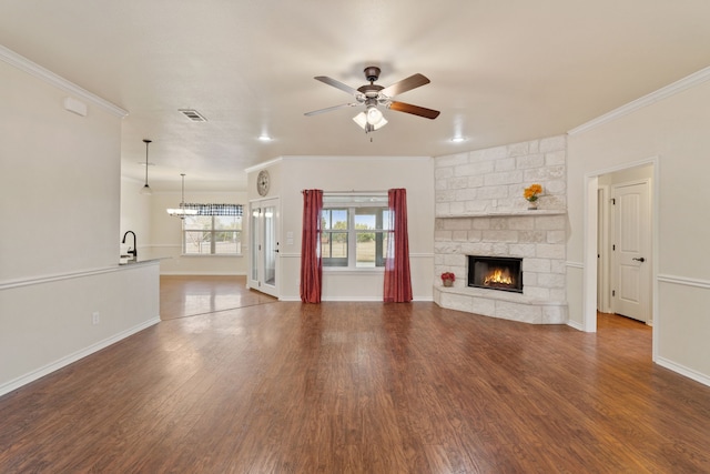 unfurnished living room with ceiling fan, ornamental molding, and a stone fireplace