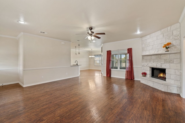 unfurnished living room featuring dark wood-type flooring, ceiling fan, ornamental molding, and a stone fireplace