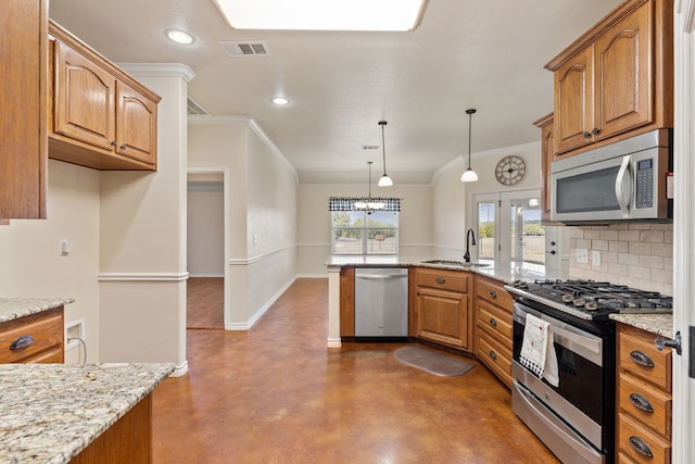 kitchen featuring stainless steel appliances, pendant lighting, crown molding, light stone counters, and sink