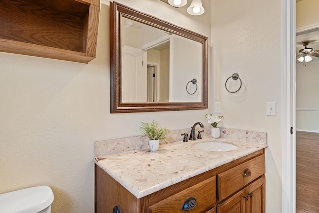 bathroom with toilet, vanity, and ceiling fan