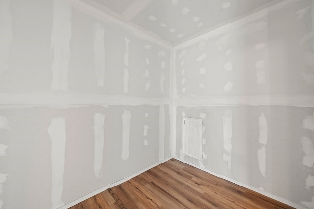 empty room with hardwood / wood-style floors and radiator heating unit