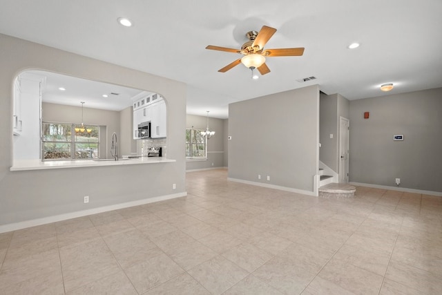 unfurnished living room featuring ceiling fan with notable chandelier and sink