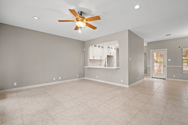 unfurnished living room with light tile patterned flooring, ceiling fan, and sink