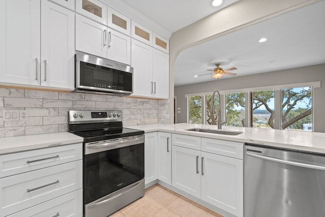 kitchen featuring sink, ceiling fan, appliances with stainless steel finishes, white cabinets, and decorative backsplash