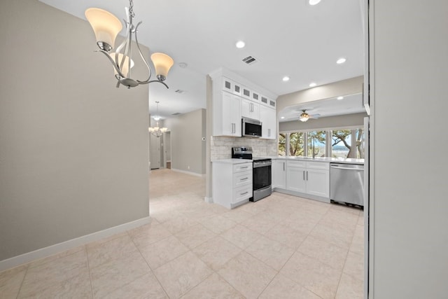 kitchen featuring appliances with stainless steel finishes, white cabinetry, tasteful backsplash, and decorative light fixtures