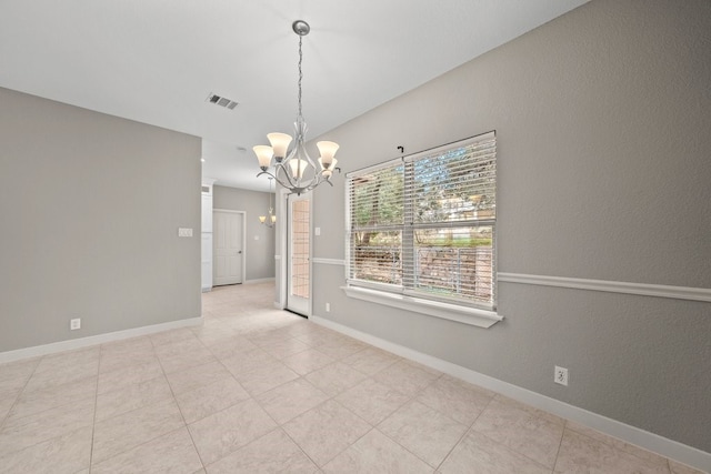 tiled spare room with a chandelier