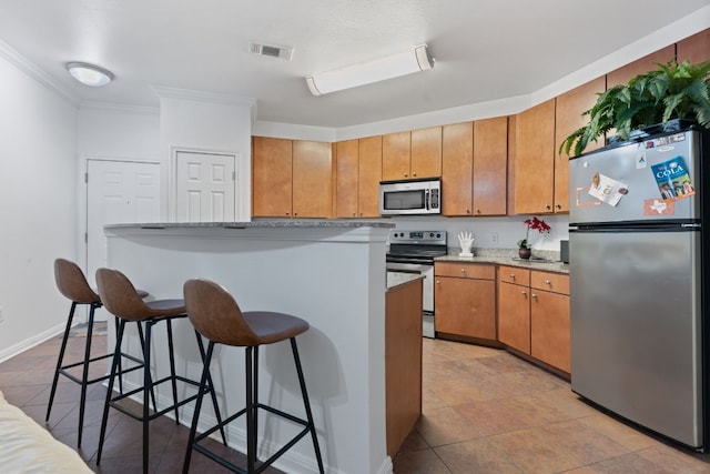 kitchen with ornamental molding, stainless steel appliances, a breakfast bar, and stone counters