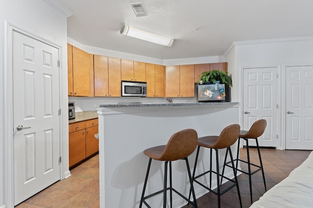 kitchen with crown molding, stainless steel appliances, and a kitchen bar