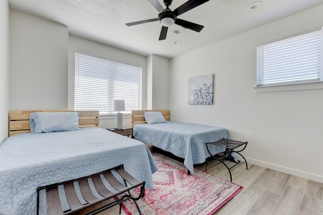 bedroom featuring ceiling fan, light hardwood / wood-style floors, and multiple windows