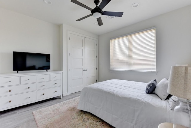 bedroom with ceiling fan, light hardwood / wood-style floors, and a closet