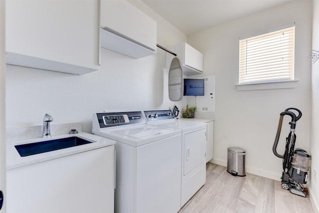 clothes washing area featuring cabinets, sink, and independent washer and dryer