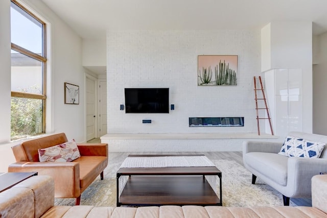 living room with a brick fireplace and light wood-type flooring