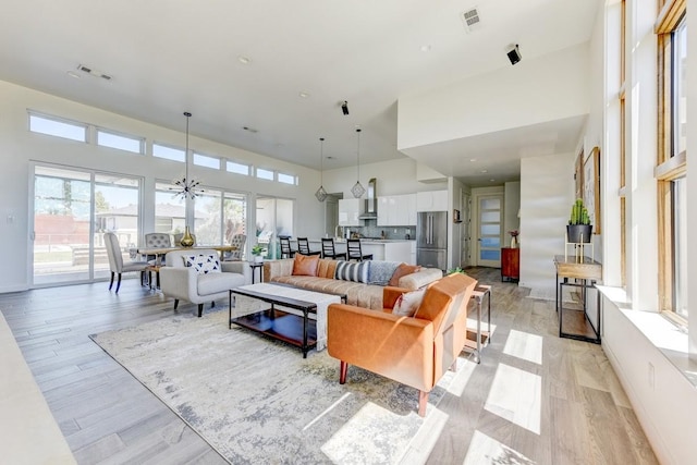 living room featuring light wood-type flooring, ceiling fan, and a high ceiling