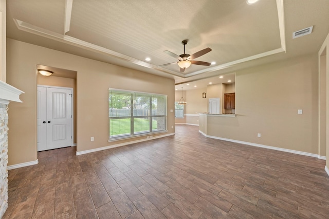 unfurnished living room with ceiling fan, a fireplace, and a tray ceiling