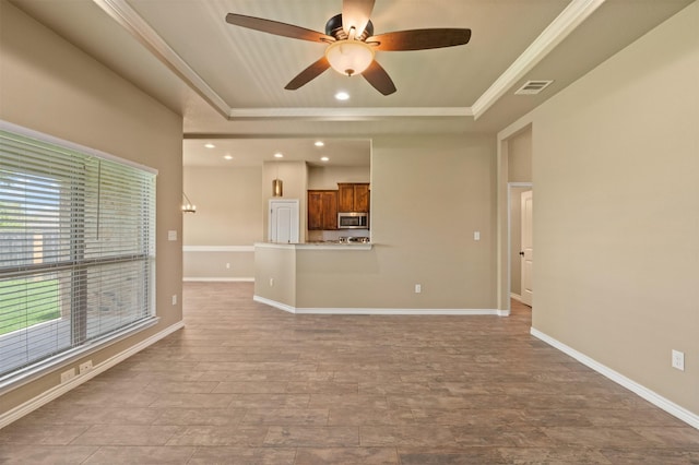 unfurnished living room with ceiling fan, a tray ceiling, light hardwood / wood-style flooring, and ornamental molding