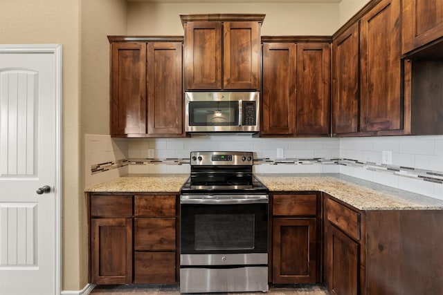 kitchen featuring decorative backsplash, light stone counters, and stainless steel appliances