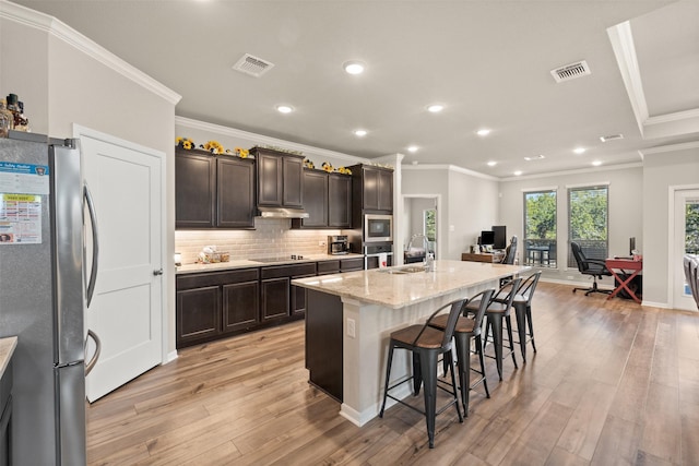 kitchen with stainless steel appliances, light wood finished floors, a sink, and visible vents