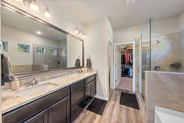 bathroom featuring wood finished floors, a sink, and a shower stall